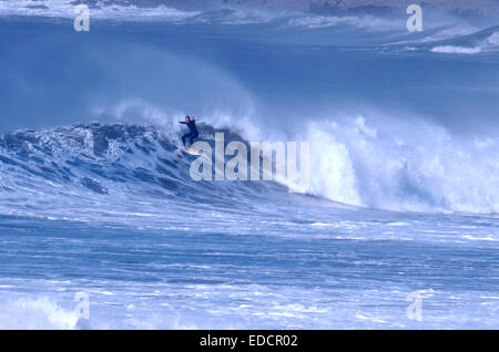 Un surfer rides une grande vague de l'Atlantique à Croyde Beach sur la côte nord du Devon, UK Banque D'Images