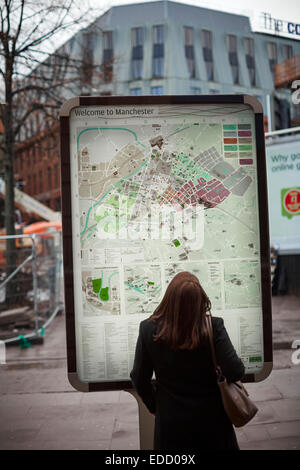 Une dame à la recherche à la carte d'une rue du centre-ville de Manchester Banque D'Images