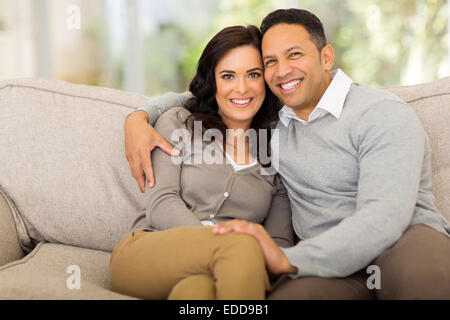 Portrait of cute couple sitting on sofa at home Banque D'Images