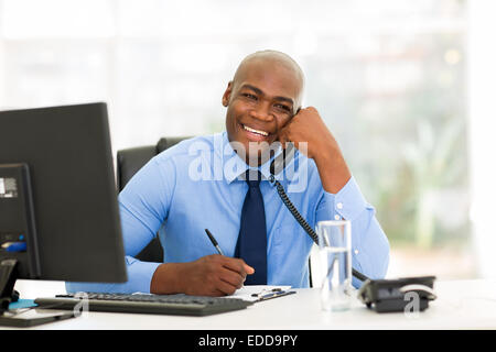 Cheerful African American businessman talking on phone dans le bureau Banque D'Images