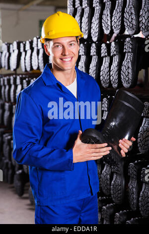 Smiling factory worker holding-boot en caoutchouc Banque D'Images