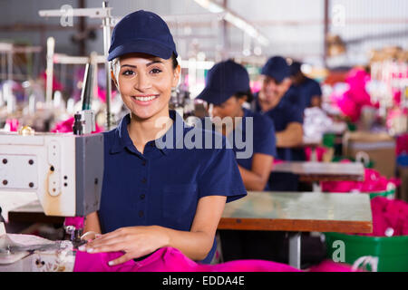 Belle jeune machiniste textiles à l'aide de machine à coudre dans l'usine de vêtements Banque D'Images