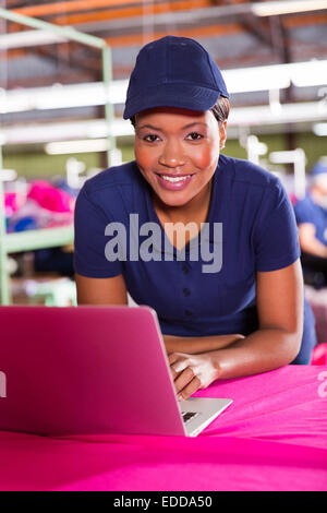 Pretty African clothing factory designer using laptop computer Banque D'Images