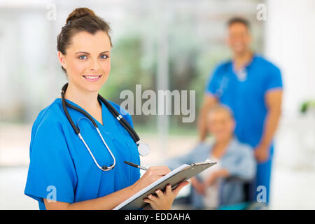 Portrait of attractive young medical doctor writing on clipboard Banque D'Images