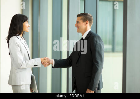 Smiling businessman handshaking avec businesswoman in office Banque D'Images