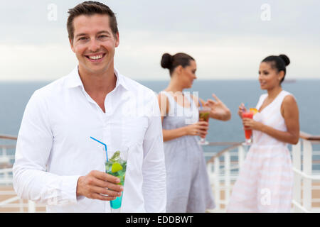 Heureux Jeune homme tenant un verre à cocktail avec des amis sur un bateau de croisière sur l'arrière-plan Banque D'Images