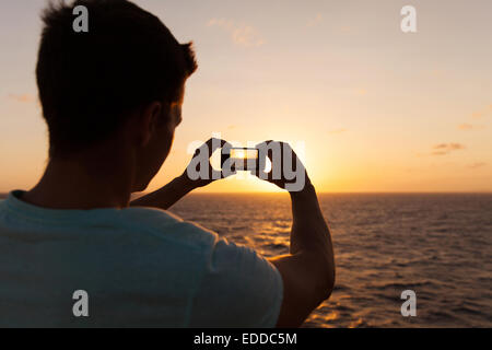 Man taking photo de beau coucher de soleil sur la mer Banque D'Images