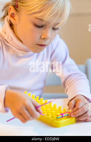 Petite fille faire loomboard avec bracelets Banque D'Images