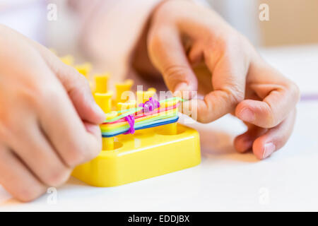 Les mains de petite fille faire loomboard avec bracelets Banque D'Images