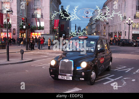 Black Cab, London taxi à Piccadilly Circus, Londres avec des lumières de Noël en arrière-plan Banque D'Images