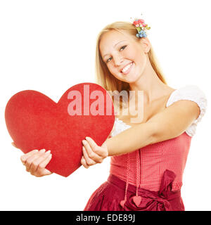 Happy woman in dirndl dress holding un gros cœur rouge Banque D'Images