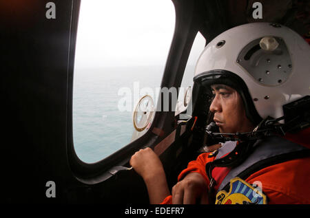 Pangkalan Bun, l'Indonésie. 6 janvier, 2015. Un membre d'équipage d'un NAS Indonesian Air Force 332 hélicoptère Super Puma regarde par la fenêtre pendant une opération de recherche pour les victimes d'AirAsia QZ 8501 sur la mer de Java au large de Pangkalan Bun, l'Indonésie, le 6 janvier 2015. L'opération de recherche pour vol AirAsia QZ8501 va se propager vers l'est un peu comme le mardi la météo et les courants de l'épave glisser dans cette direction, le chef de l'agence de sauvetage a dit. Credit : Piscine/Achmad Ibrahim/Xinhua/Alamy Live News Banque D'Images