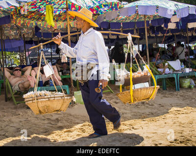 Pattaya, Pattaya, Thaïlande. 6 janvier, 2015. Un vendeur alimentaire marche dernières touristes dormir sous les parasols de location louer des chaises longues sur la plage de Pattaya. Le gouvernement thaïlandais a annoncé des plans pour nettoyer Pattaya Beach, une des plages les plus célèbres de Thaïlande. Pattaya est à environ 2,5 heures de Bangkok. Ils ont l'intention de réduire le nombre de parasol et chaise longue sur la plage et les vendeurs de réglementer les motomarines et les vendeurs le parachute ascensionnel sur la plage. Le gouvernement a déjà nettoyé les plages de l'île de Phuket et Hua Hin. Crédit : Jack Kurtz/ZUMA/Alamy Fil Live News Banque D'Images