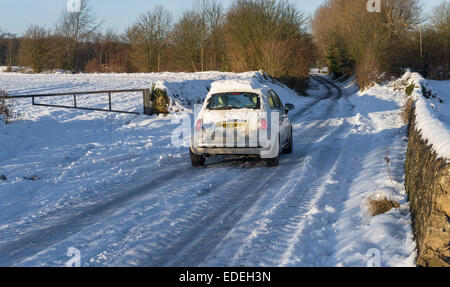 Fiat 500 blanc voiture roulant le long d'une route de campagne enneigée dans le Nottinghamshire, Angleterre. Banque D'Images