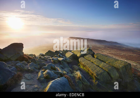 Le soleil perce les nuages beau matin illuminant le mist ci-dessous Higger Tor à la recherche jusqu'à Carl Wark dans la brume Banque D'Images