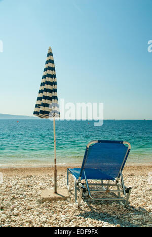 Chaises longues et parasol sur la plage à l'eau claire Banque D'Images