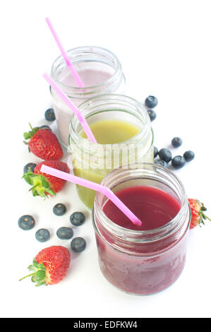 Des smoothies de fruits en pots sur un fond blanc avec des fruits Banque D'Images