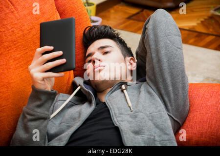 Beau jeune homme à la maison lire avec ebook reader Banque D'Images