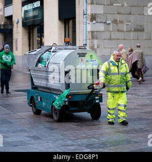 Un travail plus propre rue tirant un chariot électrique panier d'ordures dans le centre-ville de Cardiff, la capitale du Pays de Galles UK Banque D'Images