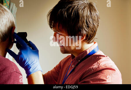 NHS mâle en portant des gants protecteurs Médecin examinant un patient dans une salle de traitement de l'hôpital Banque D'Images