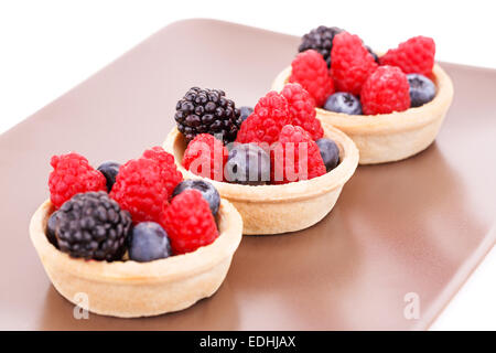 Tartelettes aux fruits frais mûrs dans sur la plaque brune. Banque D'Images