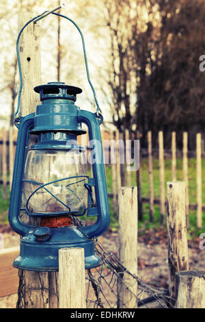 Ancien Bleu Lampe à kérosène se bloque sur une clôture extérieur en bois, tons vintage photo avec effet de filtre Banque D'Images