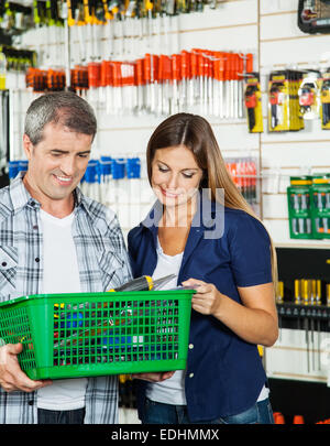 Couple carrying panier plein d'outils en magasin Banque D'Images