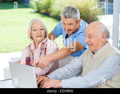 Gardien d'aider les hommes en couple Using Laptop Banque D'Images