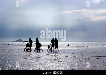 Silhouettes de deux couples avec poussettes marche sur la plage et de parler les uns avec les autres au cours d'après-midi Banque D'Images