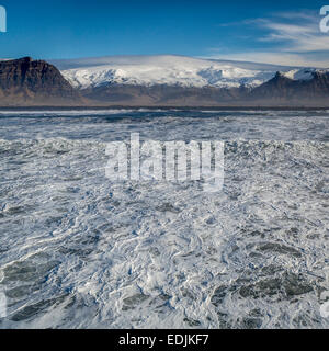 Vue aérienne de vagues déferlantes et Eyjafjallajokull Glacier en arrière-plan, Côte Sud, Islande Banque D'Images