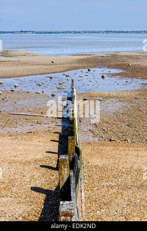 Un brise-lames en bois soleil points sur une rockpool vers un cadre tranquille Tamise comme il coule au large de l'estuaire Banque D'Images