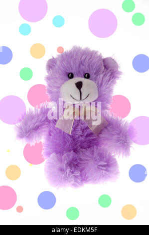 Petit ours en peluche jouet violet sur fond bleu à pois Banque D'Images