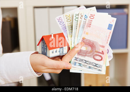 Hand holding house et euro argent comme concept pour le financement immobilier Banque D'Images