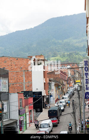 Route vallonnée avec des voitures garées tout le chemin jusqu'à d'un côté. Ville Fusagasuga, Colombie. Banque D'Images