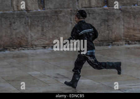 Jérusalem. Jan 7, 2015. Un garçon juif ultra-orthodoxe s'exécute dans la neige au Mur occidental dans la vieille ville de Jérusalem, le 7 janvier 2015. Cette année, la première neige a frappé Jérusalem mercredi. © Li Rui/Xinhua/Alamy Live News Banque D'Images