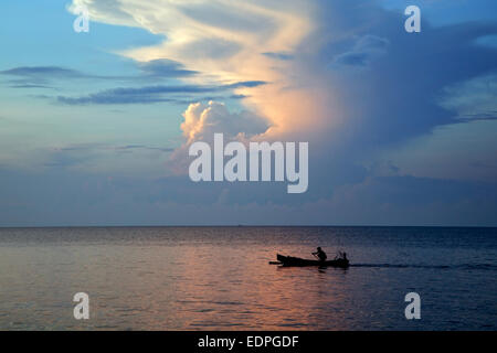 Pêcheur de l'Indonesian jukung, pirogue traditionnelle en bois, le canotage sur l'Océan Indien au coucher du soleil, Java, Indonésie Banque D'Images