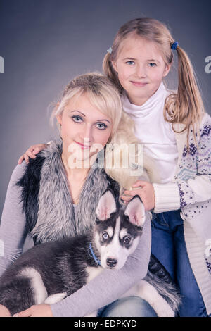 Portrait d'une jeune femme avec sa fille et un chiot Husky Banque D'Images