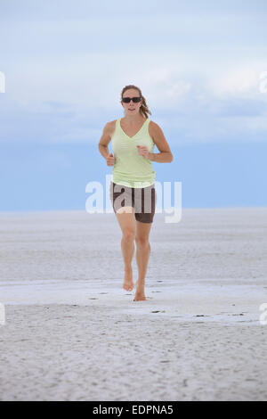 Femme portant des lunettes de soleil la course pieds nus sur l'Utah salt flats Banque D'Images