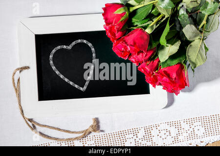 Image d'un tableau noir ardoise avec coeur avec roses rouges Banque D'Images