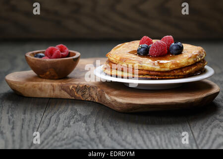 Crêpes aux framboises, bleuets et sirop d'érable, sur table en bois de chêne Banque D'Images