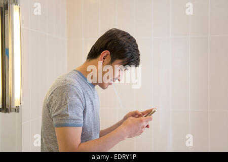 Jeune homme textos en salle de bains Banque D'Images