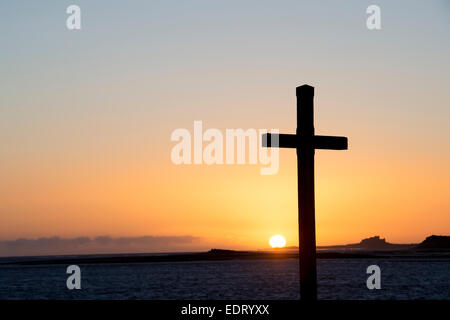 St Cuthbert's Isle croix de bois sur l'Île Sainte de Lindisfarne, au lever du soleil. Northumberland, Angleterre. Silhouette Banque D'Images