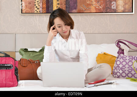 Young woman using laptop avec sacs à main autour de Banque D'Images