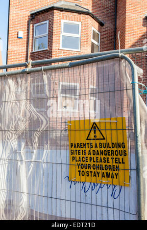 Site de construction signe de danger. Avis d'avertissement aux parents qu'un chantier est un endroit dangereux et de dire aux enfants de rester à l'écart, England, UK Banque D'Images