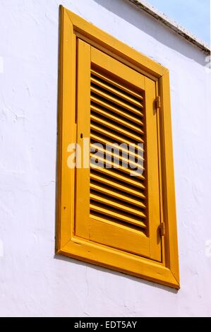 Volets peints en jaune sur le mur blanc Banque D'Images