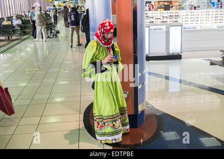 Jeune femme,femme,recharger son téléphone mobile,chargeur de téléphone,charge,dans,aéroport, à l'aéroport international de Bahreïn, Bahreïn, Moyen-Orient, Moyen-Orient Banque D'Images