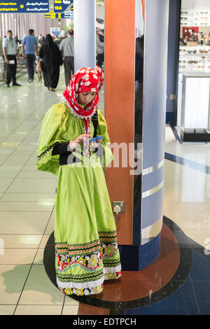 Jeune femme,femme,recharger son téléphone mobile,chargeur de téléphone,charge,dans,aéroport, à l'aéroport international de Bahreïn, Bahreïn, Moyen-Orient, Moyen-Orient Banque D'Images