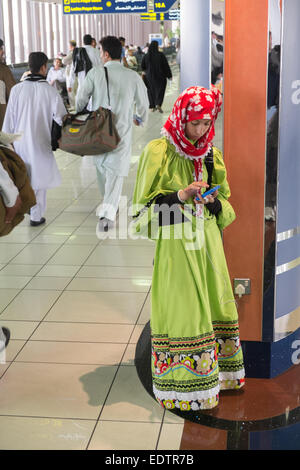 Jeune femme,femme,recharger son téléphone mobile,chargeur de téléphone,charge,dans,aéroport, à l'aéroport international de Bahreïn, Bahreïn, Moyen-Orient, Moyen-Orient Banque D'Images