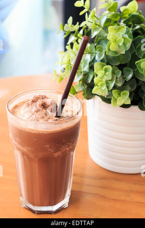 Milkshake cacao sur table en bois avec des plantes artificielles Banque D'Images