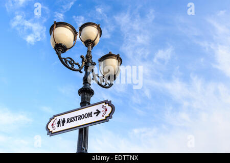 Lampe de rue et panneau à texte(WC) sur fond de ciel nuageux Banque D'Images